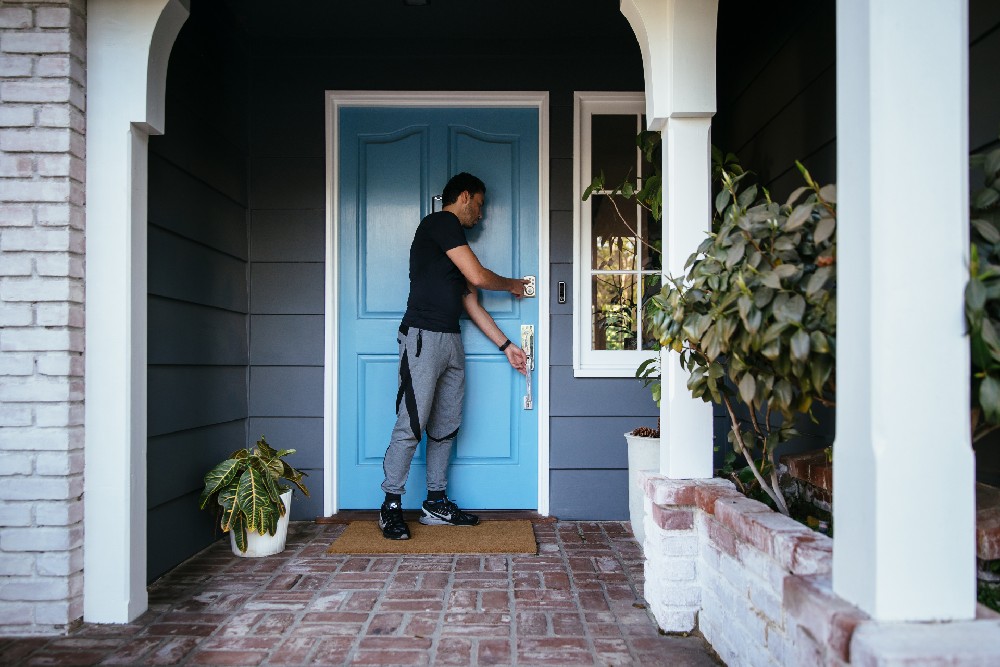 man leaving house locking smart lock