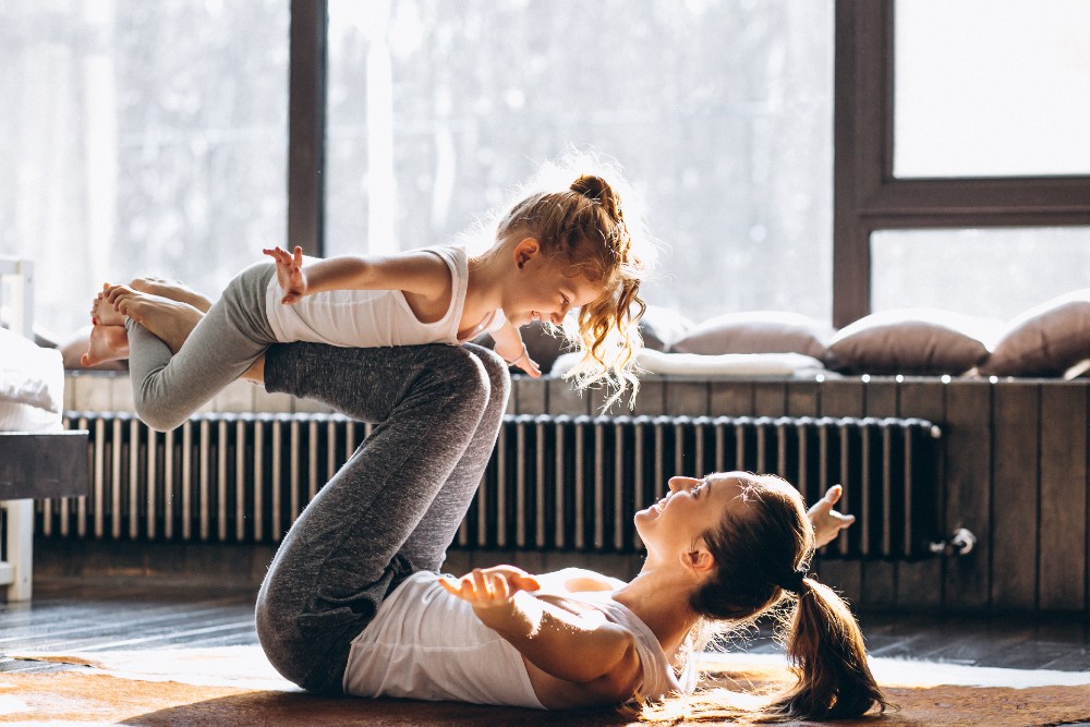 mom balancing daughter on yoga mat