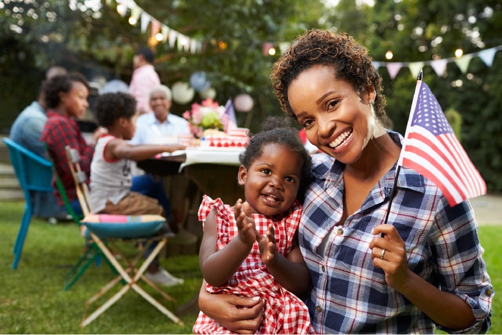 mother and daughter holding flag with family in the background