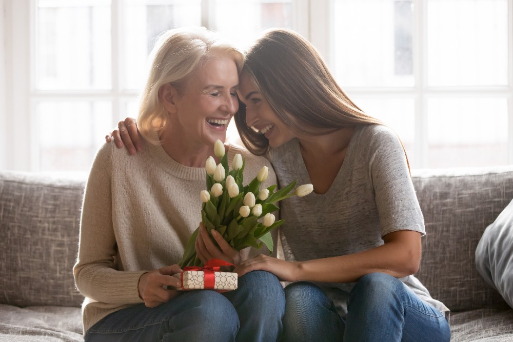 mom and daughter hugging with flowers and gift