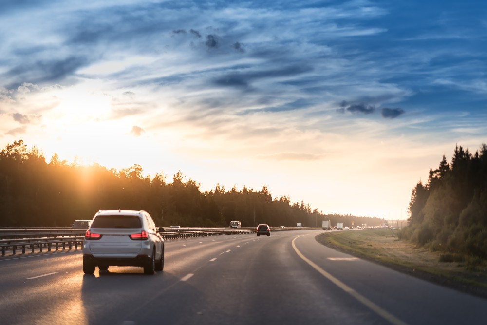 car on freeway with sunset