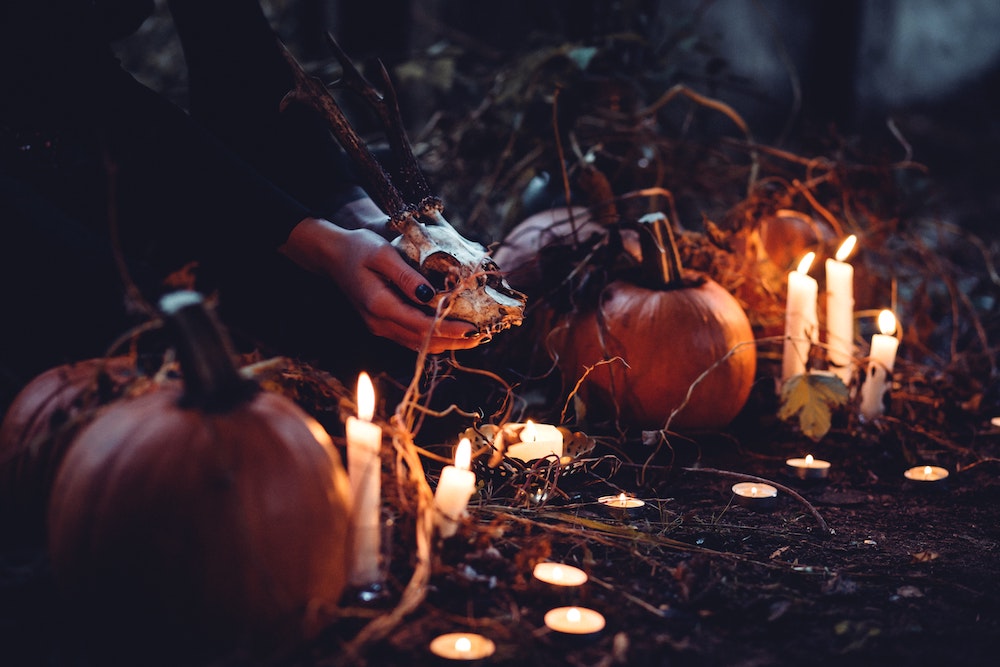 woman kneeling next to pumpkins and candles