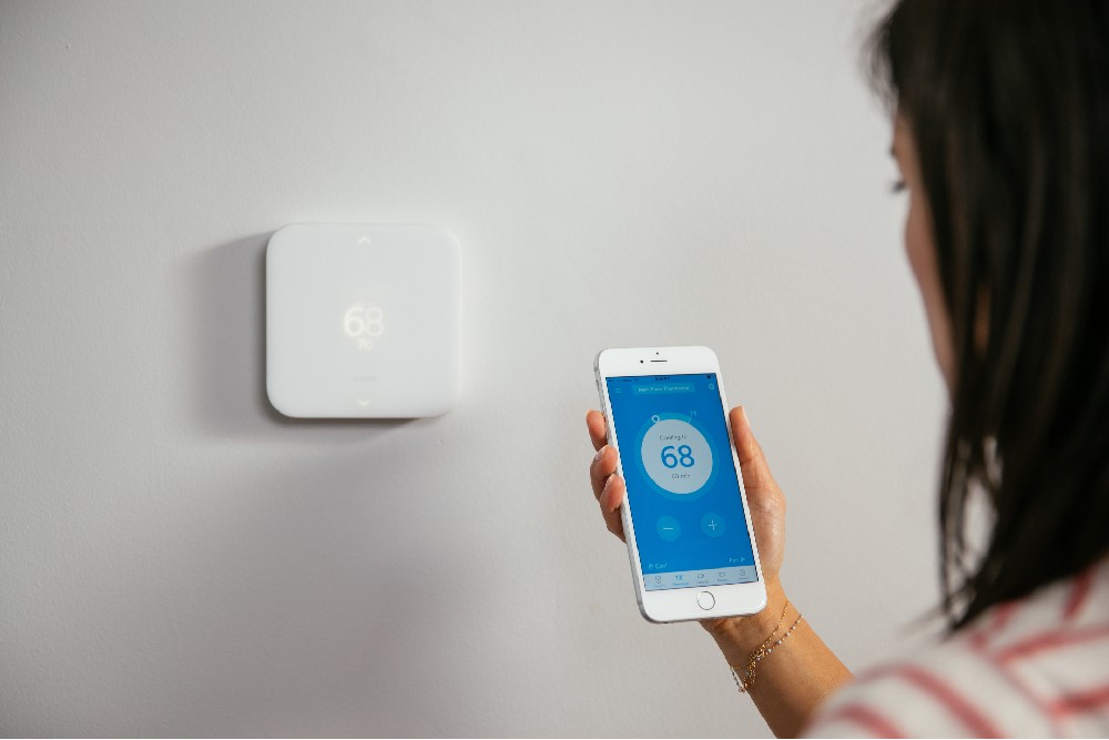 customer on app in front of smart thermostat